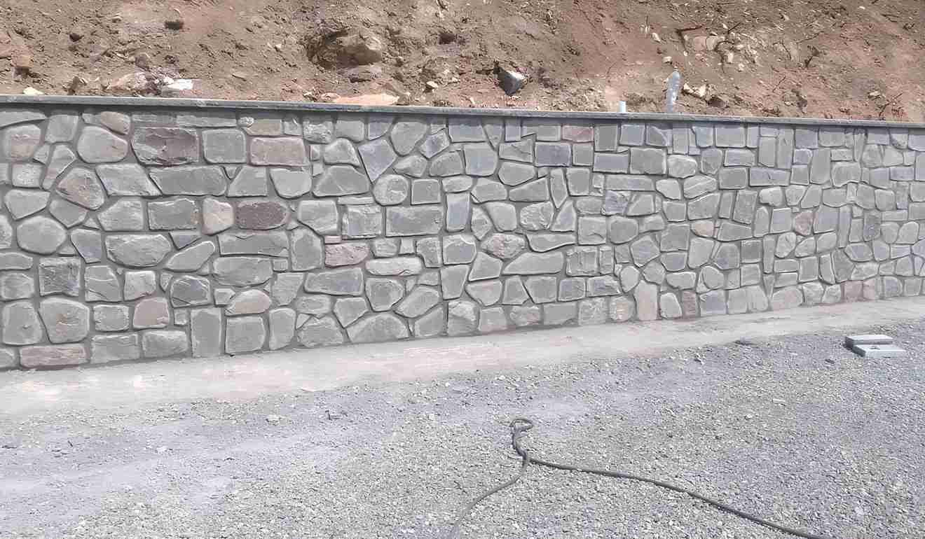Parete di contenimento con pietre a vista a lato della strada.